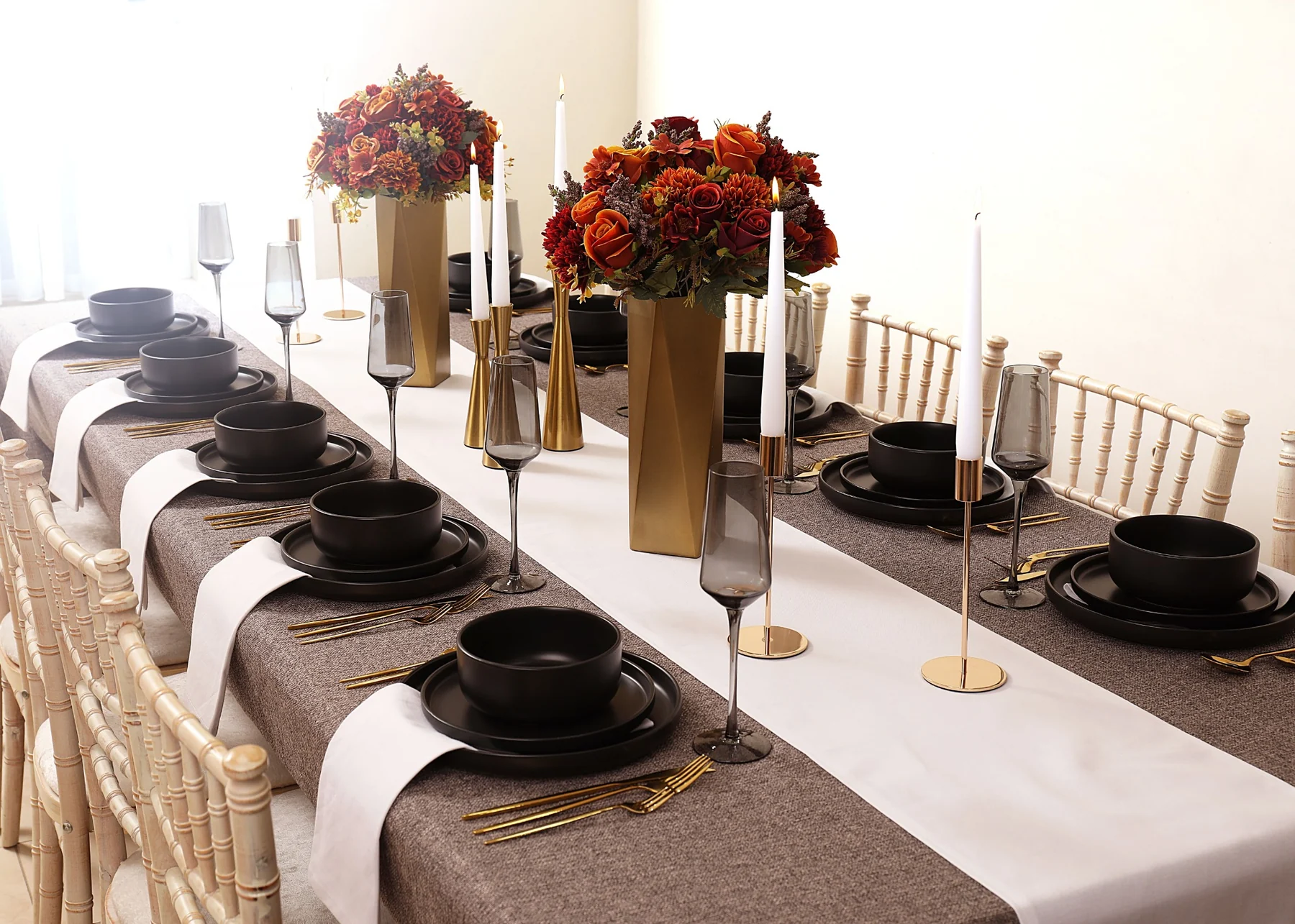 Elegant dark neutral tablescape with black dinnerware, white runners and autumnal flowers