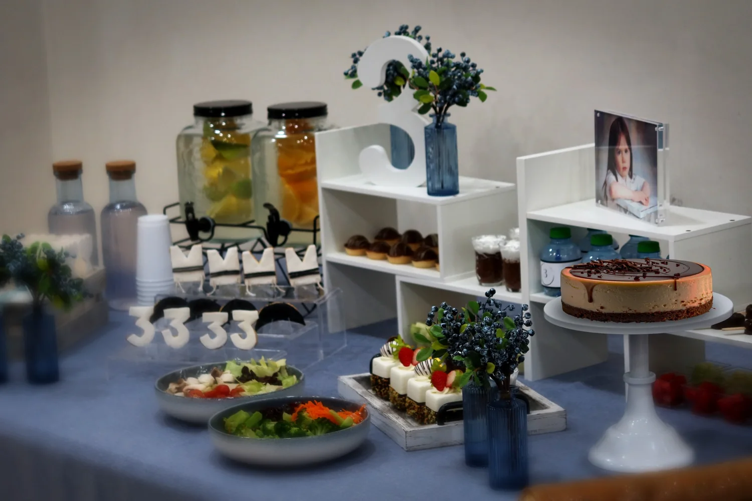 Third birthday buffet display with blue florals and a celebration cake