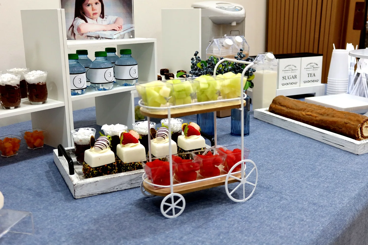 Dessert cart display with fruit cups, cakes and blue floral accents