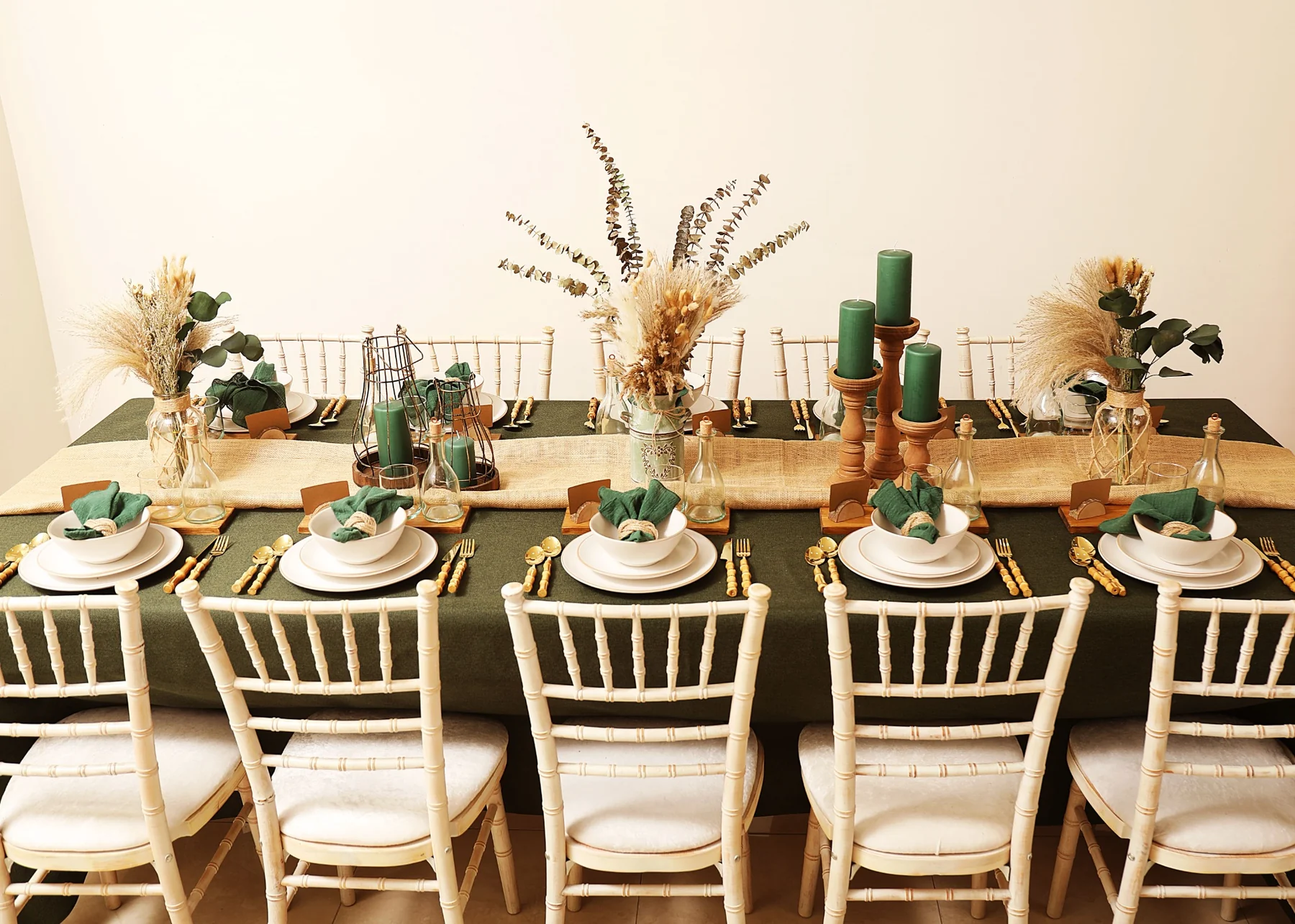 Full green, ivory and warm wood tablescape with layered place settings and dried florals