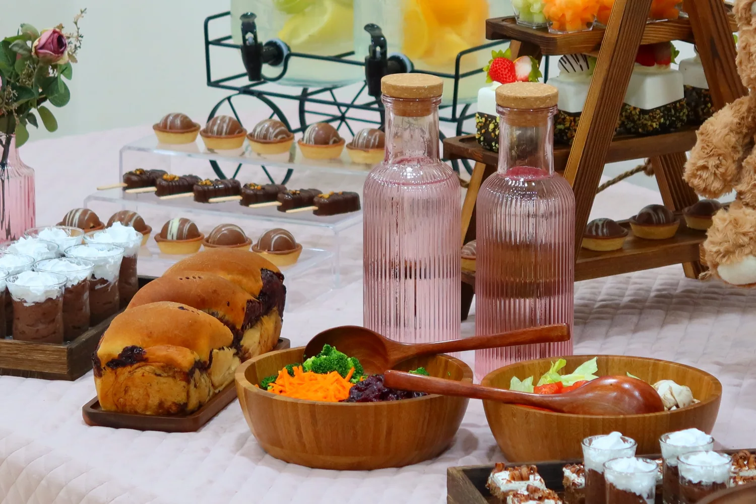 Warm brown and blush celebration table with wooden serving pieces and desserts