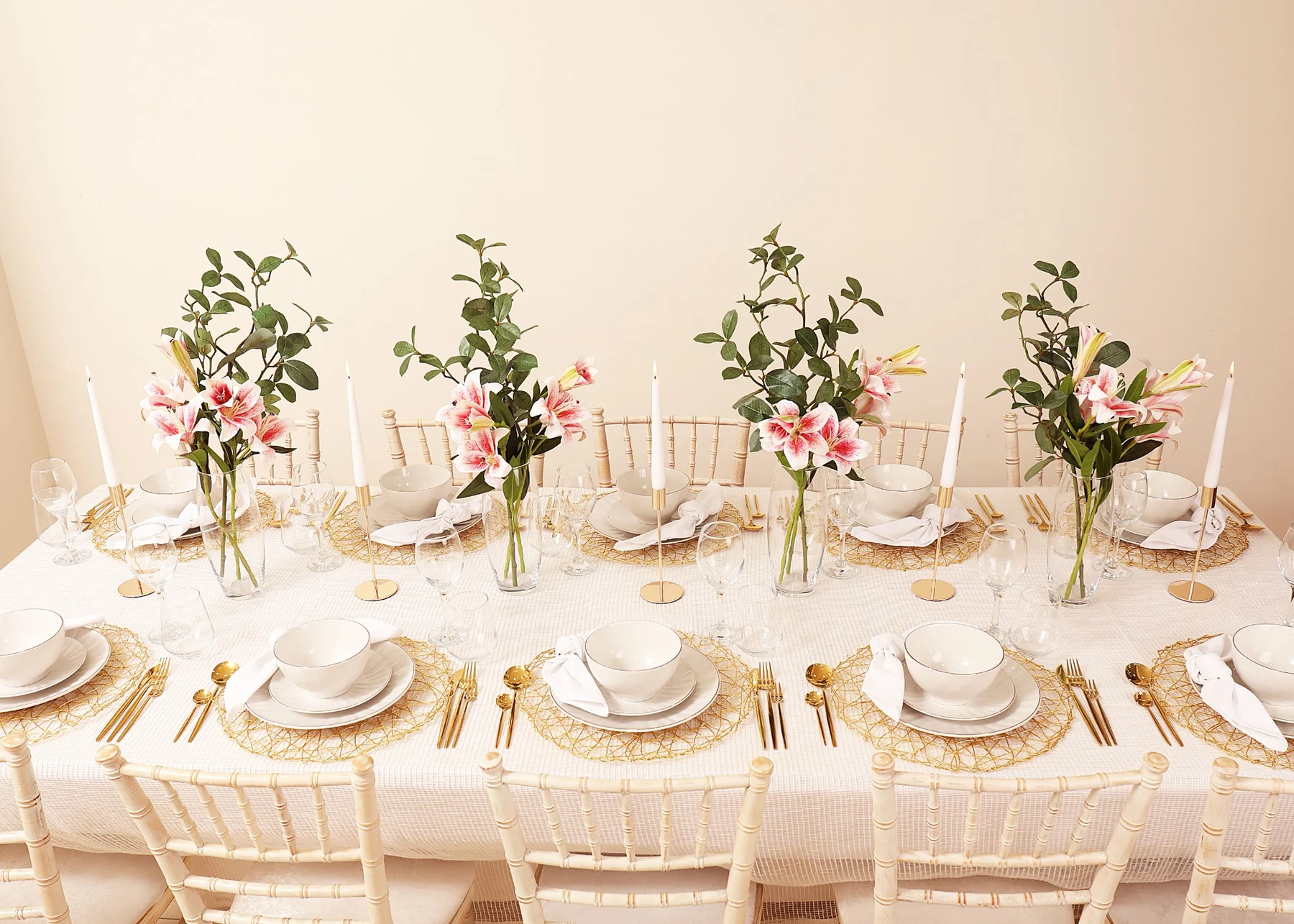 Bright white and gold tablescape with lilies, glassware and delicate candlelight